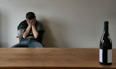 man sitting near table with bottle of alcohol
