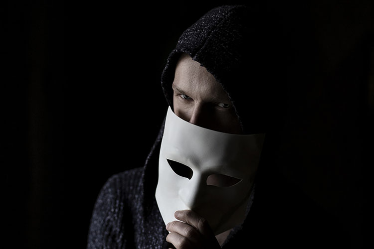 man in hoodie holding face mask