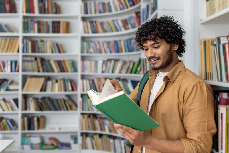 man looking at books in library