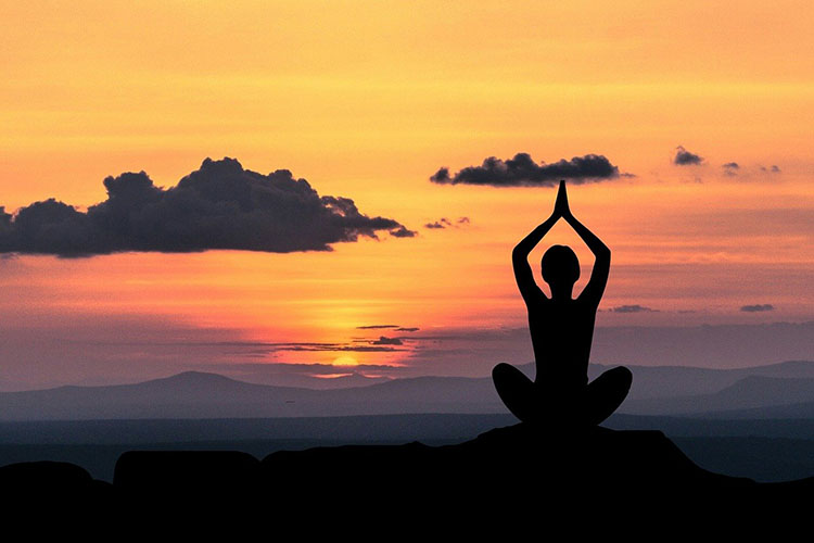 person meditating at sunset