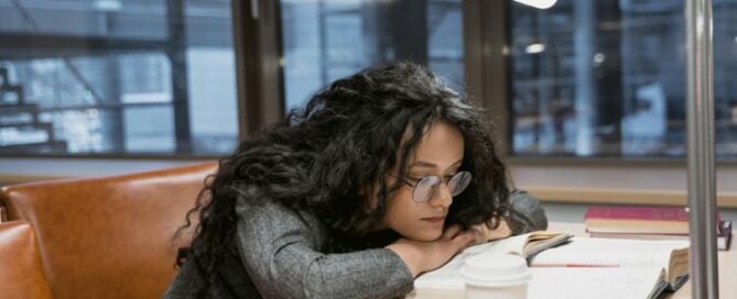woman sitting at desk with books at library