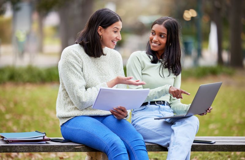 women-computers two women sitting on bench looking at computer